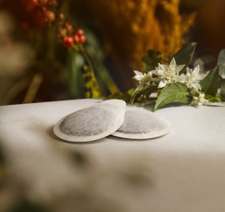 ESE paper coffee pod on a white linen table cloth with natural plants in the background