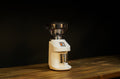 White coffee grinder with metal hopper and base, front 3/4 view