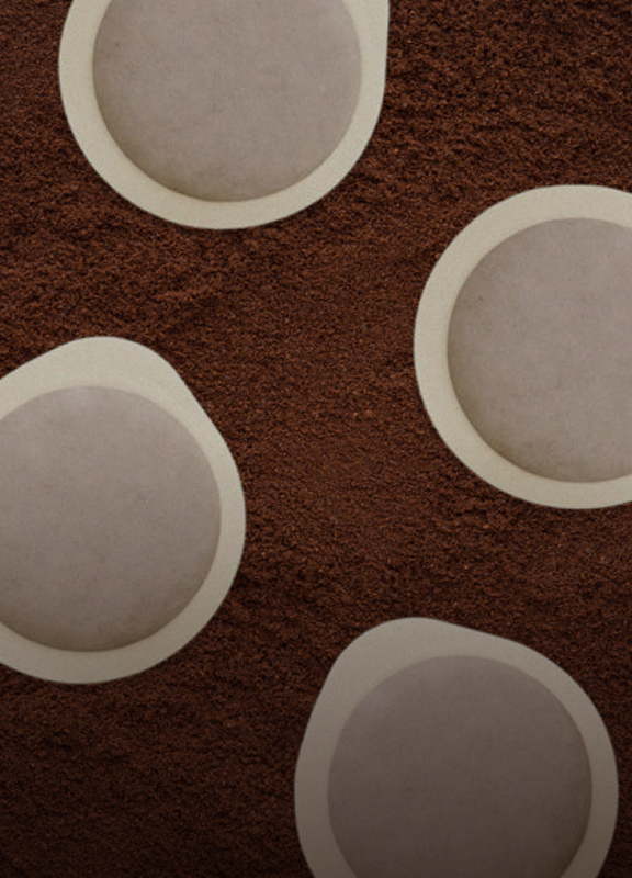 Coffee grounds with Bottega Coffee paper pods resting on top