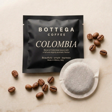 Coffee pod with white circular filter, surrounded by roasted coffee beans