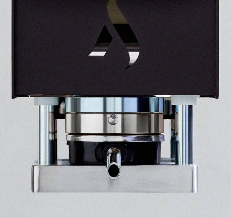 Close-up of a coffee pod in the machine with the Aroma logo on a light gray background