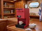 Red coffee pod machine on a counter, with a cup placed on the drip tray.